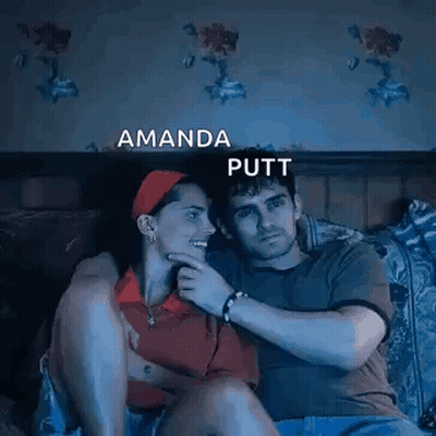 A Man And A Woman Are Sitting Next To Each Other On A Bed Watching A Movie . GIF