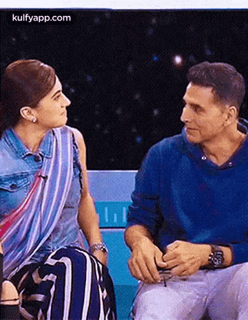 A Man And A Woman Are Sitting Next To Each Other On A Bench . GIF
