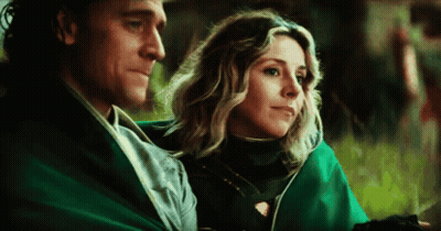 A Man And A Woman Are Sitting Next To Each Other On A Blanket . GIF