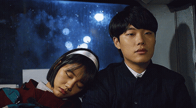 A Man And A Woman Are Sitting Next To Each Other On A Bus With Their Eyes Closed . GIF