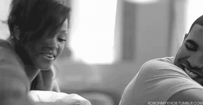 A Man And A Woman Are Sitting Next To Each Other On A Couch And Smiling . GIF