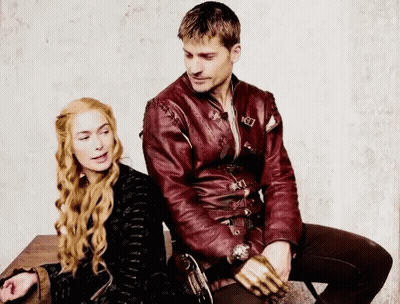 A Man And A Woman Are Sitting Next To Each Other On A Table . The Man Is Wearing A Red Leather Jacket . GIF