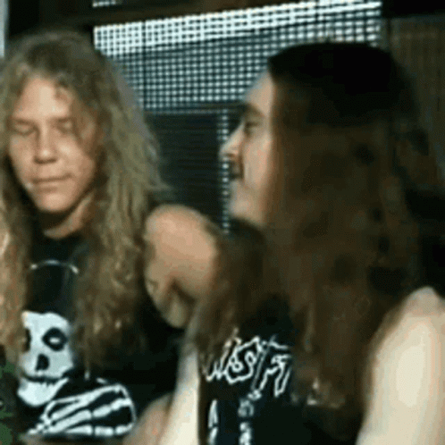 A Man And A Woman Are Sitting Next To Each Other . The Woman Is Wearing A Skull And Crossbones Shirt . GIF