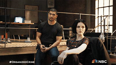 A Man And A Woman Are Sitting Next To Each Other With A Nbc Logo In The Background GIF