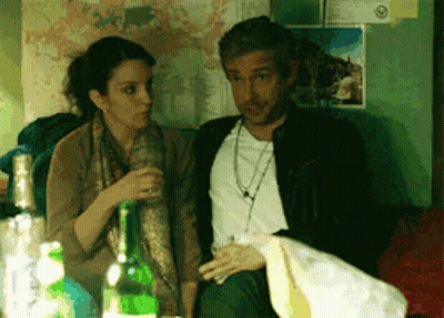 A Man And A Woman Are Sitting Next To Each Other With Bottles Of Alcohol In Front Of Them GIF