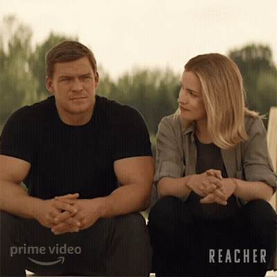 A Man And A Woman Are Sitting Next To Each Other With The Word Reacher On The Bottom Right GIF
