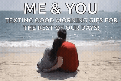 A Man And A Woman Are Sitting On A Beach Looking At The Ocean . GIF