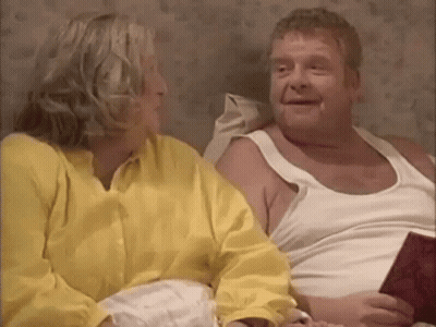 A Man And A Woman Are Sitting On A Bed And Talking To Each Other . GIF