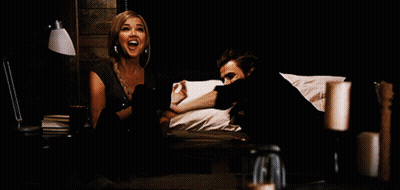 A Man And A Woman Are Sitting On A Bed And The Woman Is Screaming GIF