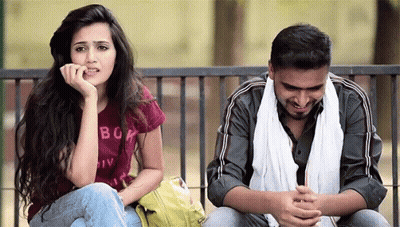 A Man And A Woman Are Sitting On A Bench And The Woman Is Wearing A Shirt With The Word Boa On It GIF