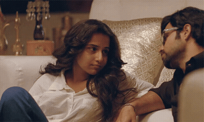 A Man And A Woman Are Sitting On A Couch GIF
