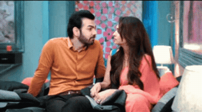 A Man And A Woman Are Sitting On A Couch And Talking To Each Other . GIF