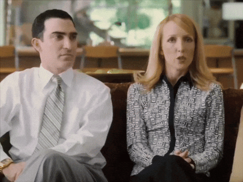 A Man And A Woman Are Sitting On A Couch And The Man Is Wearing A White Shirt And Tie GIF