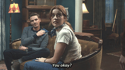 A Man And A Woman Are Sitting On A Couch And The Woman Is Asking If They Are Okay GIF