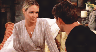 A Man And A Woman Are Sitting On A Couch And The Woman Is Wearing A Polka Dot Top GIF