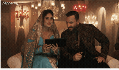 A Man And A Woman Are Sitting On A Couch Looking At A Tablet With Pepperfry Written On The Bottom GIF