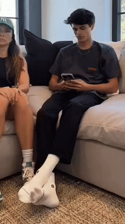 A Man And A Woman Are Sitting On A Couch Looking At Their Cell Phones GIF