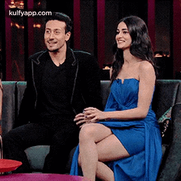 A Man And A Woman Are Sitting On A Couch Talking To Each Other . GIF