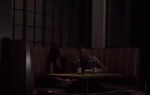 A Man And A Woman Are Sitting On A Couch With Two Bottles Of Beer . GIF
