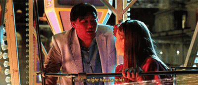 A Man And A Woman Are Sitting On A Ferris Wheel And The Man Is Talking To The Woman . GIF