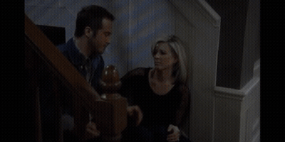 A Man And A Woman Are Sitting On A Set Of Stairs Talking To Each Other GIF