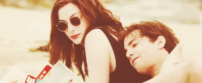 A Man And A Woman Are Sitting On The Beach . GIF