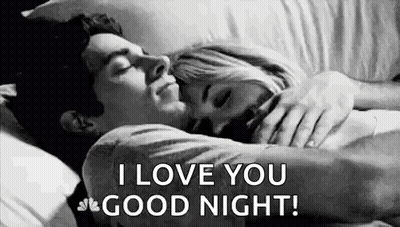 A Man And A Woman Are Sleeping In A Bed And The Man Is Hugging The Woman . GIF