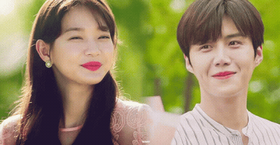 A Man And A Woman Are Smiling And Looking At The Camera GIF