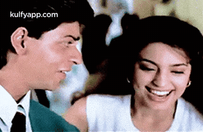 A Man And A Woman Are Smiling At Each Other . GIF
