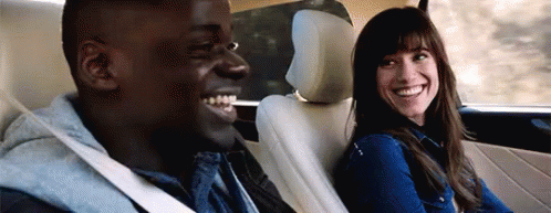 A Man And A Woman Are Smiling In The Back Seat Of A Car . GIF