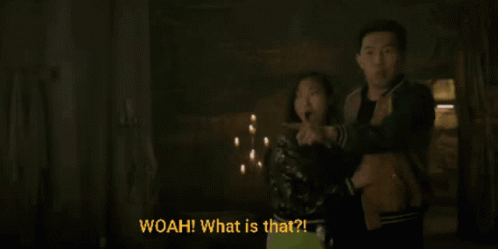 A Man And A Woman Are Standing In A Dark Room And The Woman Is Pointing At Something And The Man Is Saying Woah What Is  GIF