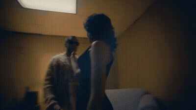 A Man And A Woman Are Standing In A Dark Room GIF