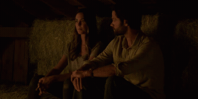 A Man And A Woman Are Standing In A Dark Room With A Light On The Ceiling GIF