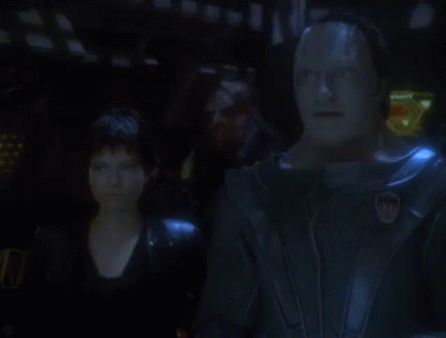 A Man And A Woman Are Standing In A Dark Room With The Words It 'S Working GIF