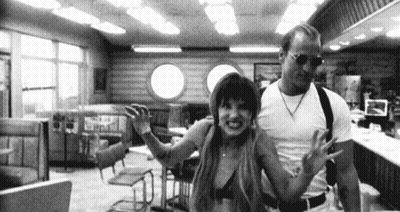 A Man And A Woman Are Standing In A Diner . GIF