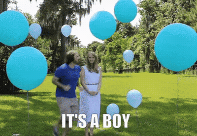A Man And A Woman Are Standing In A Field With Balloons And The Words It 'S A Boy GIF
