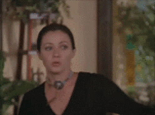 A Man And A Woman Are Standing In A Hallway Looking At A Door GIF