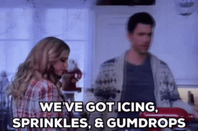 A Man And A Woman Are Standing In A Kitchen And The Woman Is Saying `` We 'Ve Got Icing , Sprinkles GIF