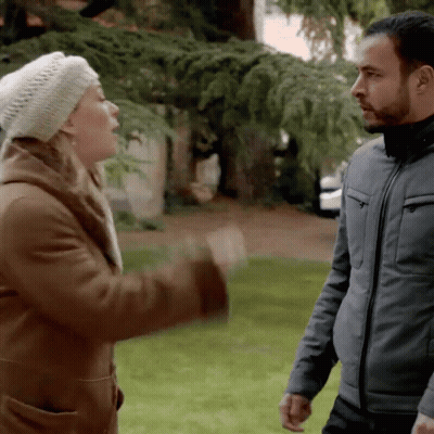 A Man And A Woman Are Standing In A Park GIF