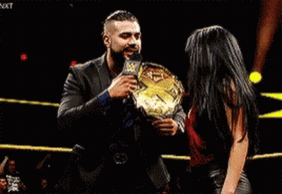 A Man And A Woman Are Standing In A Ring Holding A Championship Belt . GIF
