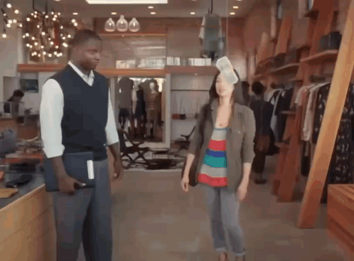 A Man And A Woman Are Standing In A Store GIF