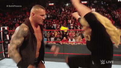 A Man And A Woman Are Standing In A Wrestling Ring . GIF