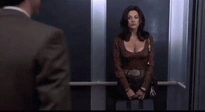 A Man And A Woman Are Standing In An Elevator . GIF