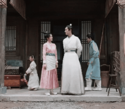 A Man And A Woman Are Standing In Front Of A Building GIF