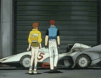 A Man And A Woman Are Standing In Front Of A Car With The Number 5 On It GIF