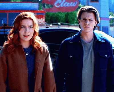 A Man And A Woman Are Standing In Front Of A Claw Restaurant GIF