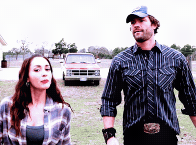 A Man And A Woman Are Standing In Front Of A Dodge Truck With A Texas License Plate GIF
