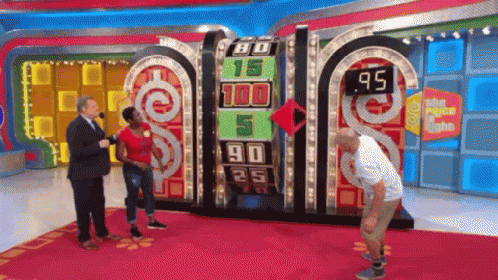 A Man And A Woman Are Standing In Front Of A Game Board That Says 80 15 100 5 90 25 And 95 GIF
