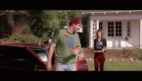 A Man And A Woman Are Standing In Front Of A House . GIF
