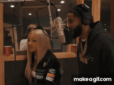 A Man And A Woman Are Standing In Front Of A Microphone With Make A Gif.com In The Corner GIF